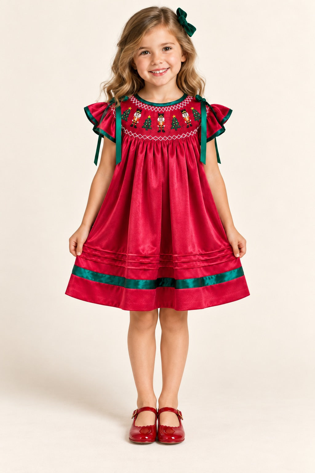 Girl modeling the red Nutcracker holiday dress with green bows and hem trim, wearing red shoes.